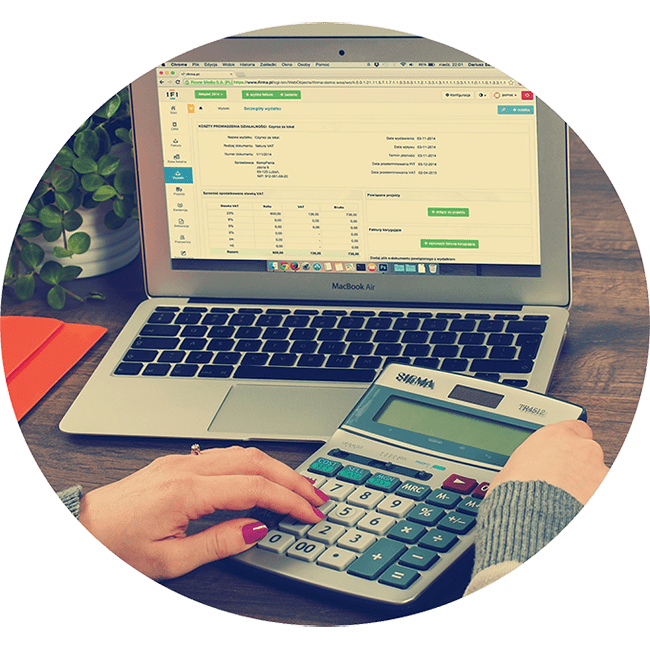Hand using calculator in front of laptop