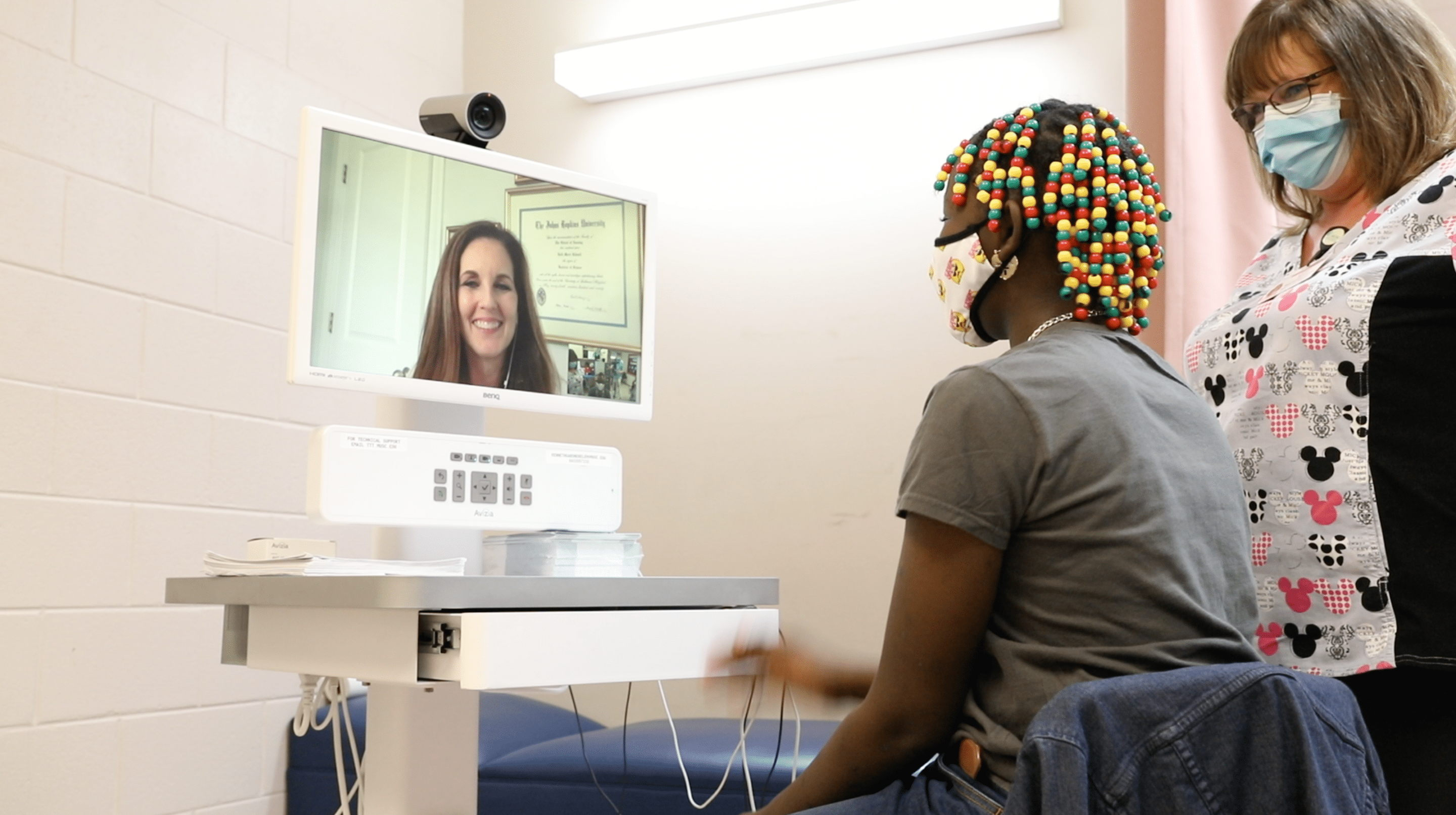 A picture of a child and school nurse doing a telehealth visit.