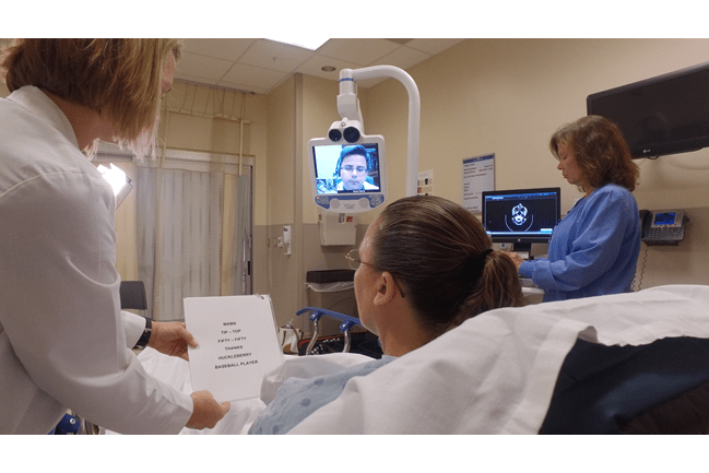 A picture of a woman in the hospital getting tested by physician via telehealth.