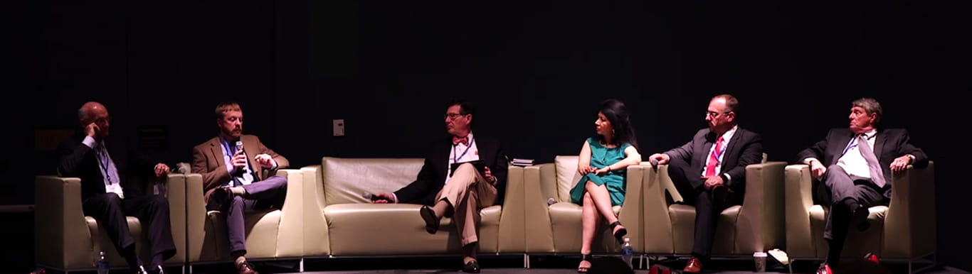 Group of people sitting on sofas on a stage. 