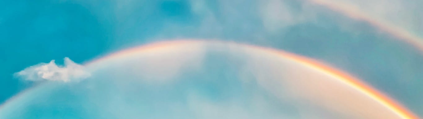 A partly cloudy sky with a double rainbow in it. 