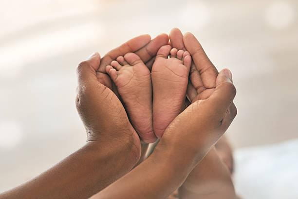 Hands cradling an infant's feet.