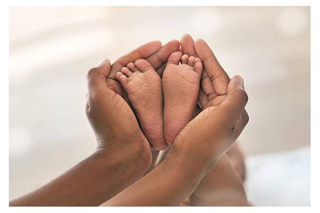 Hands cradling an infant's feet.
