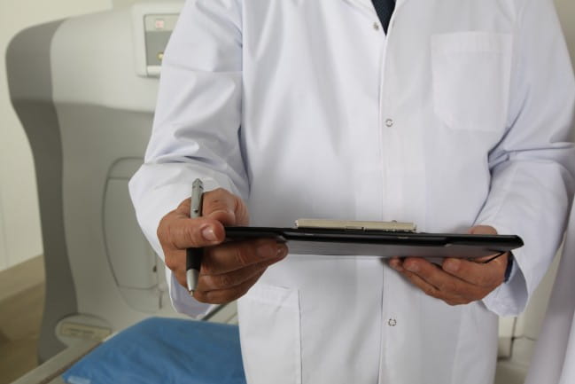 Image of person in white coat holding a clip board